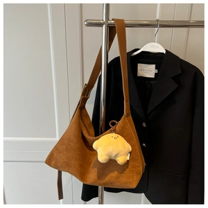 Brown frosted suede hobo bag with a star plush charm hanging on a hanger