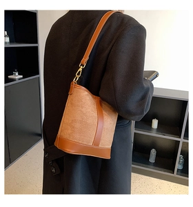 Brown patchwork bucket bag shown on model featuring suede texture and gold hardware detail