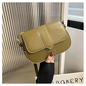 Detail der senfgrünen Satteltasche aus Kunstleder mit Goldbeschlägen und Vertikalriemen