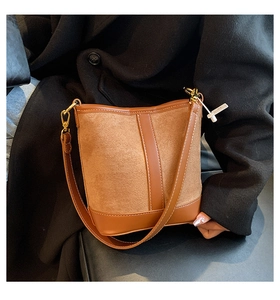 Close-up of caramel brown contrast bucket bag showing suede texture and golden metal hardware