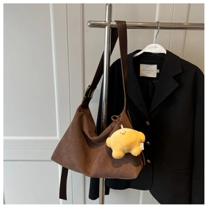 Close-up of brown frosted suede hobo bag with a yellow plush star charm on a hanger
