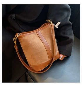 Detail of brown contrast bucket bag with gold hardware and suede stitching