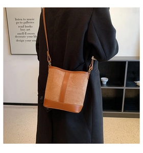 Detail view of tan patchwork bucket bag with suede texture and leather trim worn by model