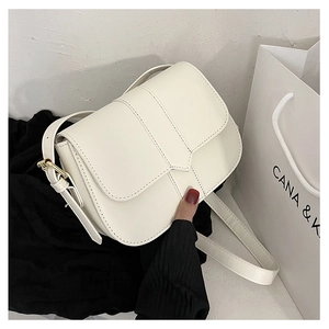Detailansicht der cremeweißen Satteltasche mit Kunstlederstruktur und goldener Hardware