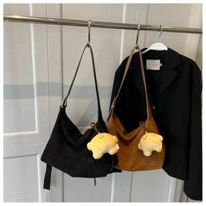 Detail of half-moon suede tote bags in black and brown with star plush charm on a hanger