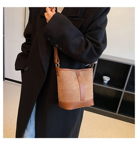 Detail of a brown patchwork bucket bag in suede and smooth leather on a model