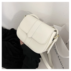 Detailansicht der weißen Leder-Satteltasche mit goldenen Beschlägen vor schlichtem Hintergrund