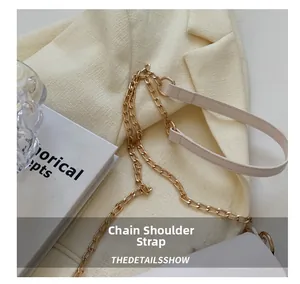 Detail of elegant gold metal chain shoulder strap with white leather and round hardware