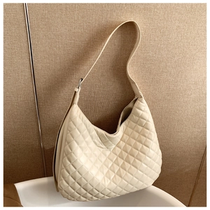 Detailed close-up of a beige quilted crossbody bag with textured faux leather finish