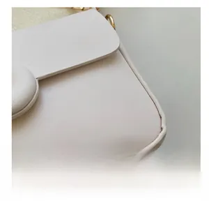 Detailed close-up of cream leather crossbody bag featuring fine stitching and golden buckle
