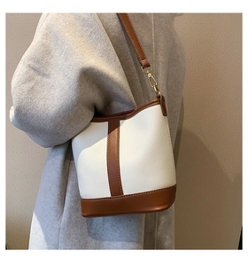 Detail view of contrast color bucket bag with white litchi and brown leather texture