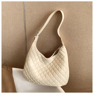Close-up of quilted diamond pattern on beige hobo bag with adjustable strap details
