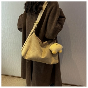 Detail of ginger suede tote bag with adjustable strap and star charm on wool coat