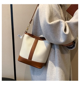 Detail of a contrast bucket bag with beige pebble grain leather and brown leather trim