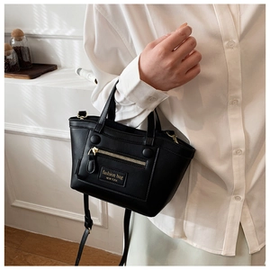 Détail du sac en cuir noir mat avec poche zippée dorée et bandoulière réglable pratique