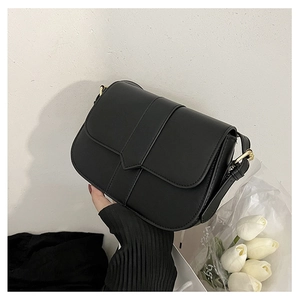 Schicke schwarze Satteltasche mit Goldbeschlägen vor einem minimalistischen Hintergrund