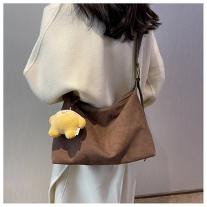 Macro shot of dark brown matte suede tote bag with cute yellow plush charm on model