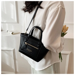 Détail du sac à main en cuir noir avec fermetures éclair décoratives et logo mode