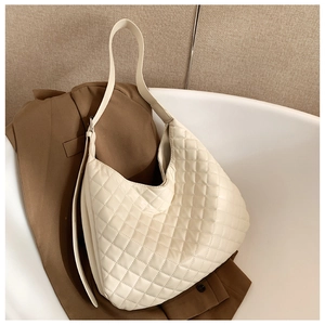 Detail of creamy white quilted shoulder bag with large capacity on brown blazer