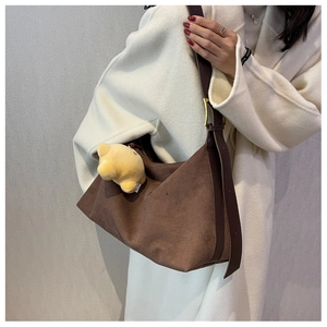 Detail of dark brown matte Hobo bag with wide strap and plush pendant on model
