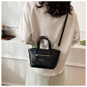 Détail du mini sac cabas noir avec fermeture éclair dorée porté par un mannequin