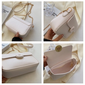 Detail view of cream crossbody bag featuring metal chain strap and interior zip pocket