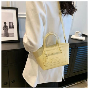 Détail d'un petit sac cabas carré jaune crème avec fermeture éclair et poignées supérieures