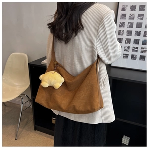 Detail of a brown matte suede tote bag with a yellow star charm on a female model