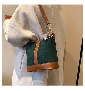 Detail of green suede and brown leather bucket bag with gold hardware on long coat
