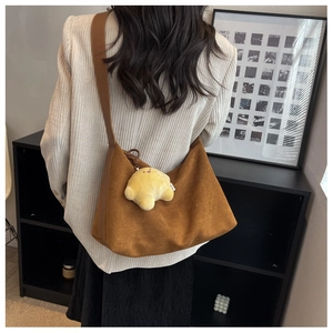Brown corduroy hobo bag with leather strap and cute plush charm on a casual outfit