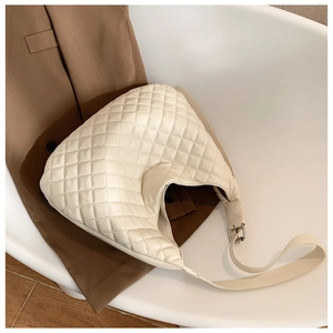 Close-up of beige quilted hobo bag with adjustable strap and premium metal hardware details