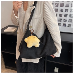 Detail of black suede crescent bag with yellow star plush charm and long shoulder strap