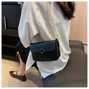 Close-up of a classic black leather crossbody bag with chain strap and button detail