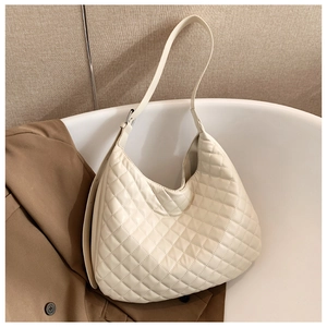 Detail of a beige quilted hobo bag with a refined diamond stitch and adjustable strap