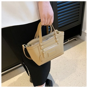 Vue détaillée du sac bandoulière en similicuir beige avec deux poignées et lanière