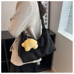 Side view of a large black matte shoulder bag with a cute yellow star plush pendant