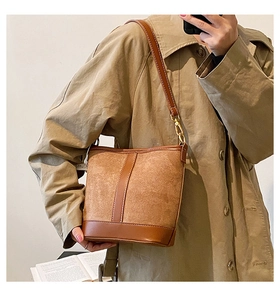 Detail of a brown bucket bag in mixed suede and smooth leather on a model outfit