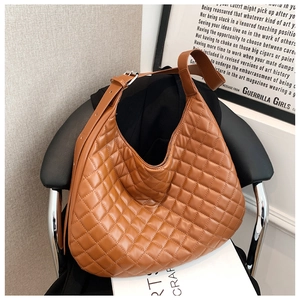 Detailed view of a brown quilted hobo bag with adjustable strap on a chair