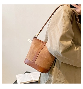 Detail of vintage brown leather and suede patchwork bucket bag with gold metal buckle