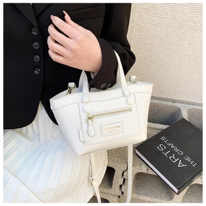 Détail du sac à main en cuir blanc montrant la poche zippée et les doubles poignées