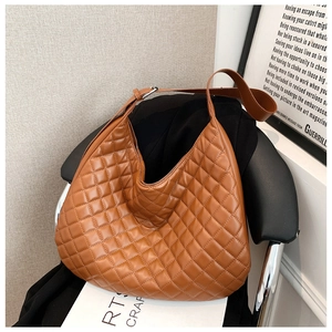 Detail of caramel brown quilted shoulder bag with smooth leather and silver buckle