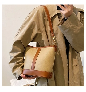 Detail of a two-tone bucket bag with lychee texture and gold-tone metal hardware