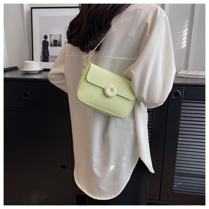 Detail of light green crossbody bag featuring a 3D flower buckle and gold chain strap