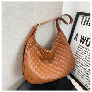 Detail of a brown quilted leather crescent bag showing stitching and silver buckle