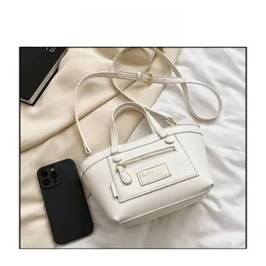 Vue détaillée de dessus d'un sac en cuir blanc avec logo doré sur tissu beige