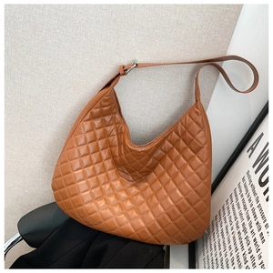Detail of a brown quilted hobo bag featuring a crescent shape and silver metal hardware