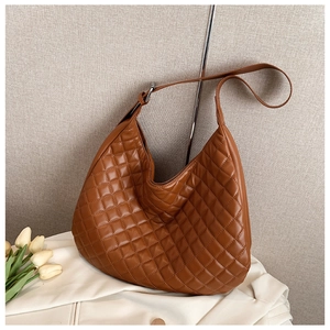 Close-up of brown quilted hobo bag with adjustable strap and silver metal buckle