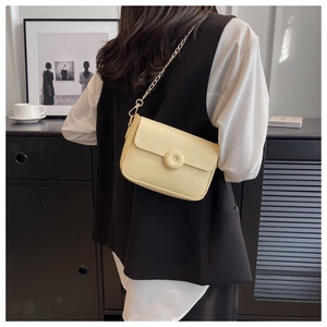 Detailed close-up of cream square crossbody bag with gold chain strap on a model