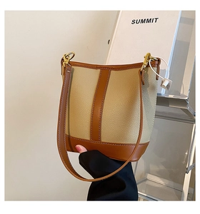 Detailed close-up of a beige and brown contrast bucket bag with gold-tone hardware
