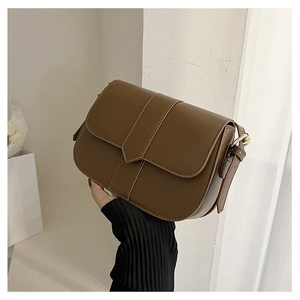 Detailansicht einer braunen Satteltasche mit goldenen Beschlägen und Lederriemen